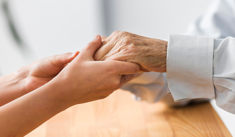 A professional caregiver assisting a senior patient with dressing in a private room at an Assisted living Parkinson's near Delhi facility.